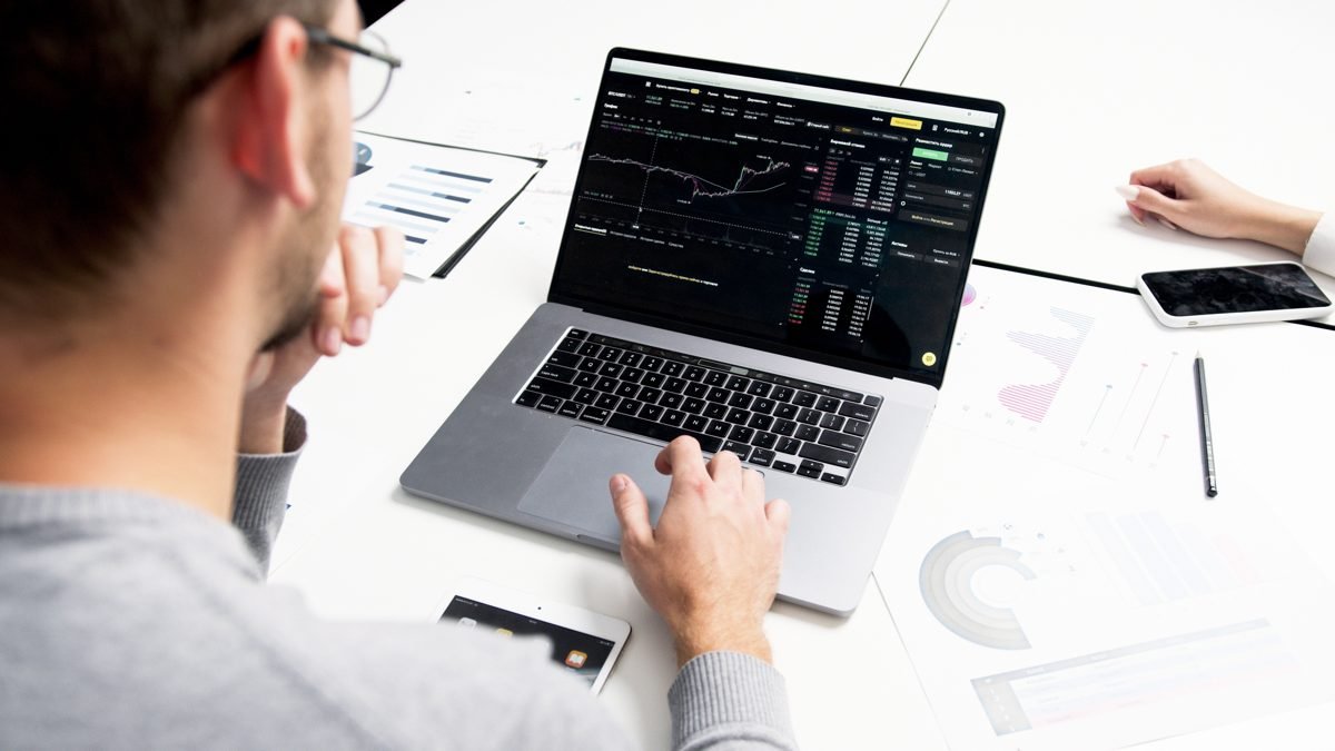 Pessoa analisando dados de investimentos e mercado financeiro em notebook