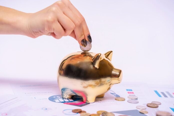 Mão colocando moeda em cofrinho dourado cercado de documentos financeiros, simbolizando proteção e segurança da poupança