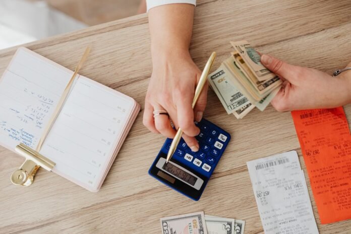 Mãos organizando contas, recibos e calculadora sobre mesa de madeira para planejamento financeiro