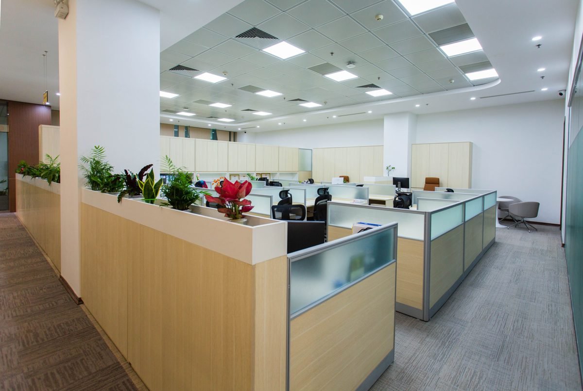 Interior de escritório corporativo contemporâneo com andar corrido, divisórias de vidro fosco, plantas e estações de trabalho