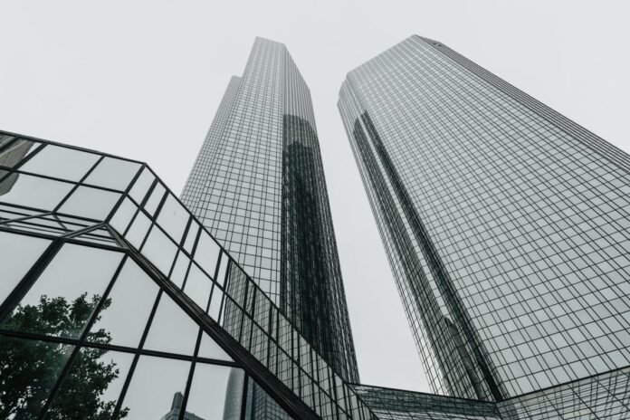Vista de baixo para cima de duas torres corporativas de vidro espelhado, estilo dos edifícios modernos da região da Faria Lima/Chucri Zaidan em São Paulo