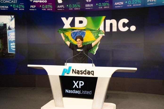 Guilherme Benchimol, fundador da XP, ergue a bandeira do Brasil no púlpito da Nasdaq na cerimônia de estreia da XP Inc. na bolsa americana