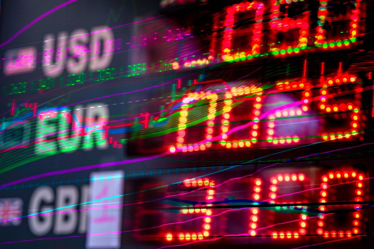 Painel digital de cotações exibindo símbolos de moedas (USD, EUR, GBP) com dados de mercado ao fundo