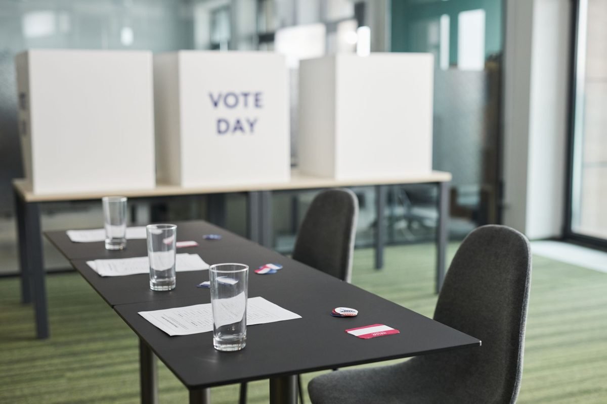 Cabines de votação vazias com mesa de apoio, sem eleitores presentes, representando uma seção eleitoral antes da votação