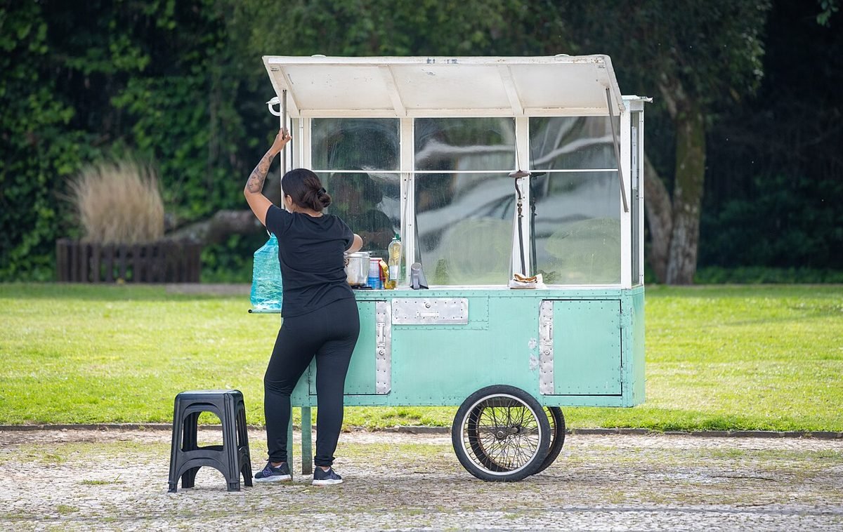 Vendedora ambulante atendendo um carrinho de comércio de rua ao ar livre