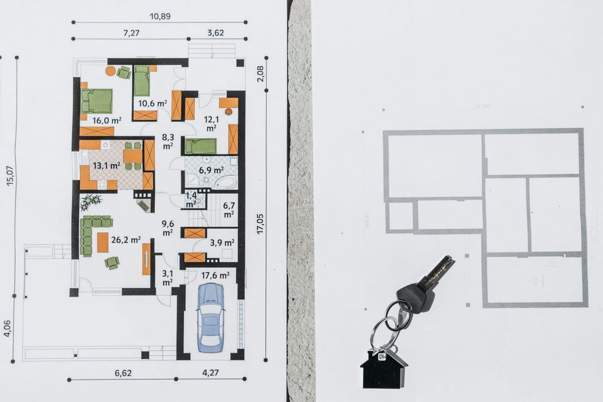Chaveiro em formato de casa sobre plantas baixas de uma residência impressas em papel