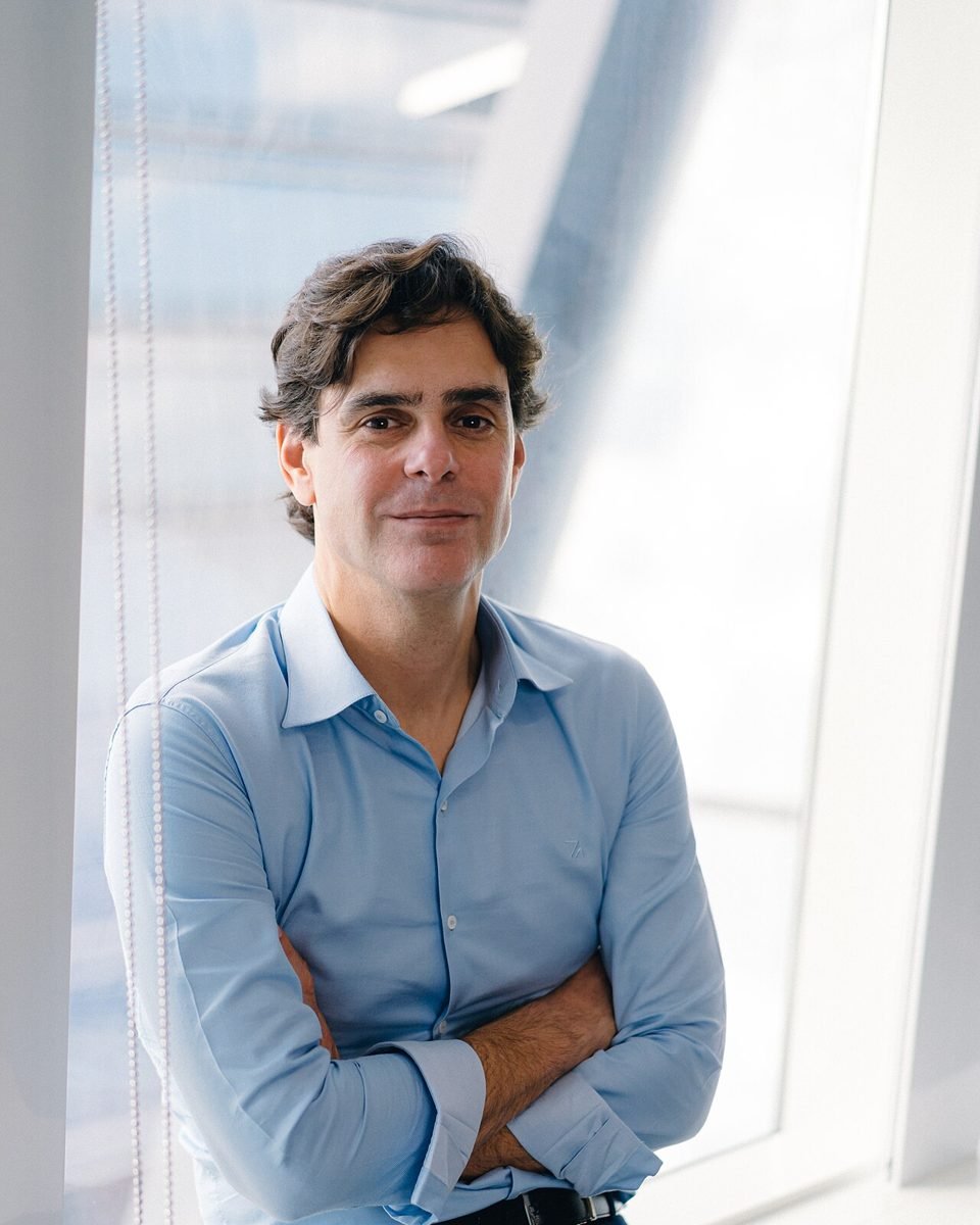 Guilherme Benchimol, fundador e presidente do conselho da XP Inc., de braços cruzados em ambiente corporativo