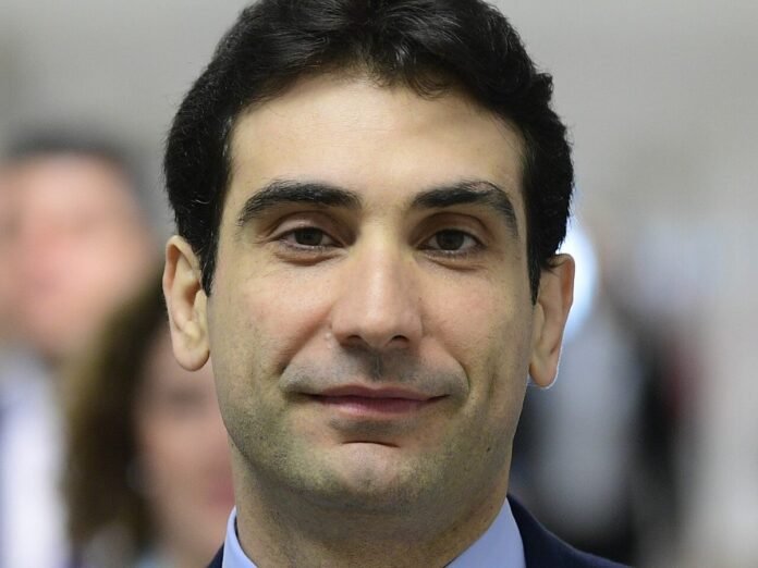 Retrato de Gabriel Galípolo, presidente do Banco Central, de terno escuro e gravata vermelha